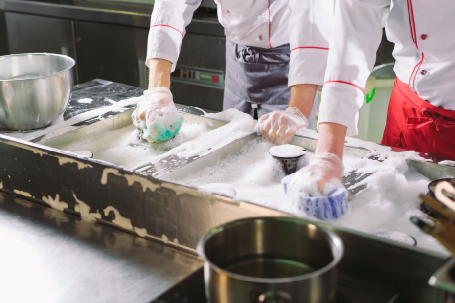 two people in a kitchen cleaning equipment