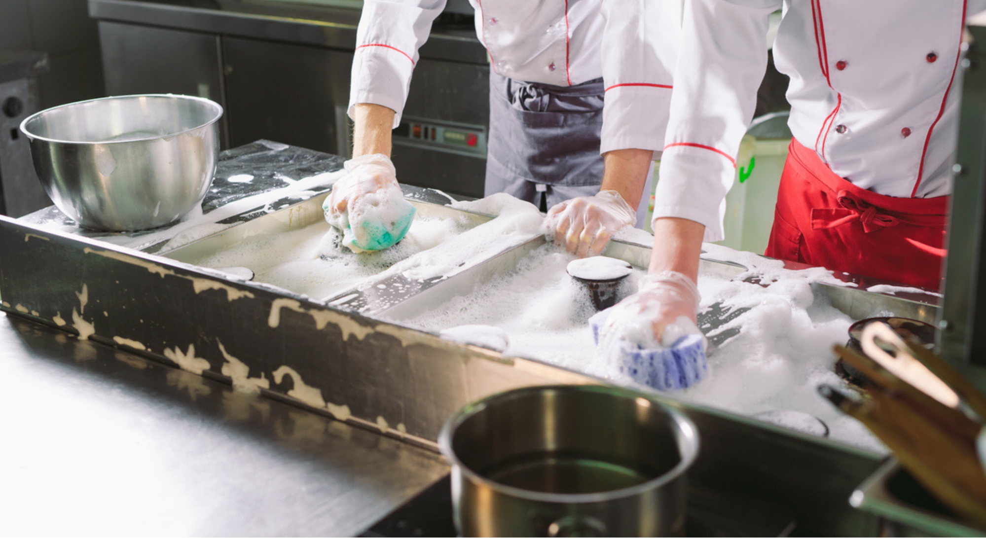 two people in a kitchen cleaning equipment