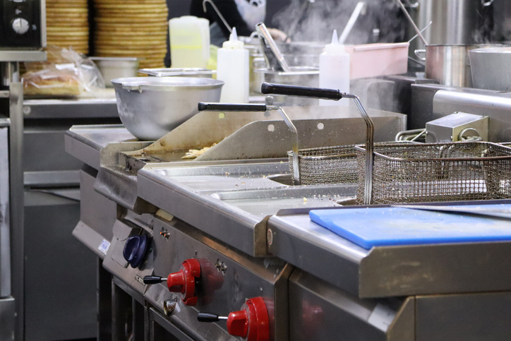 A bustling commercial kitchen filled with various cooking equipment, fryers, and multiple preparation areas