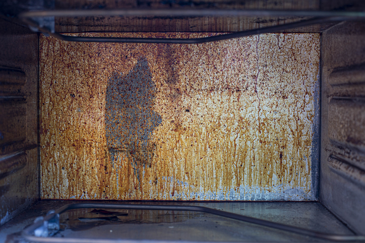 the back wall of the gas oven splattered with grease and smoke, the front and background are blurred