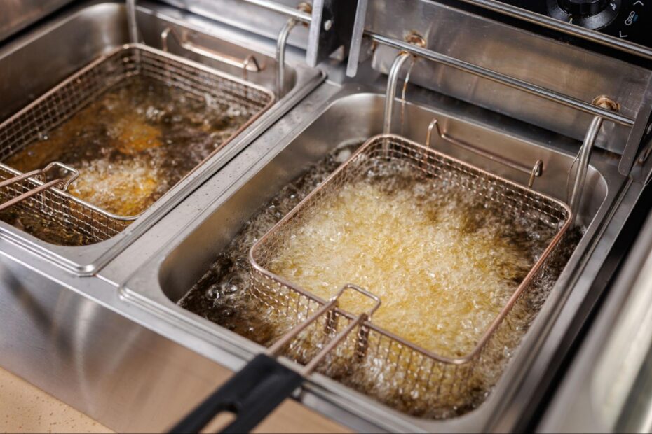 Commercial deep fryers with baskets submerged in bubbling hot cooking oil.
